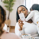 Black mother holding her baby while reading affirmation cards that say 'I am proud of myself' during a mindful moment at the table