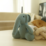 Handmade blue crochet elephant toy sitting on a modern coffee table in a cozy living room with natural light and minimalist decor