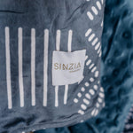 Kijani Throw Blanket in teal with geometric patterned front and solid textured back — large 60" x 80" African-inspired reversible blanket by Sinzia Comfort.