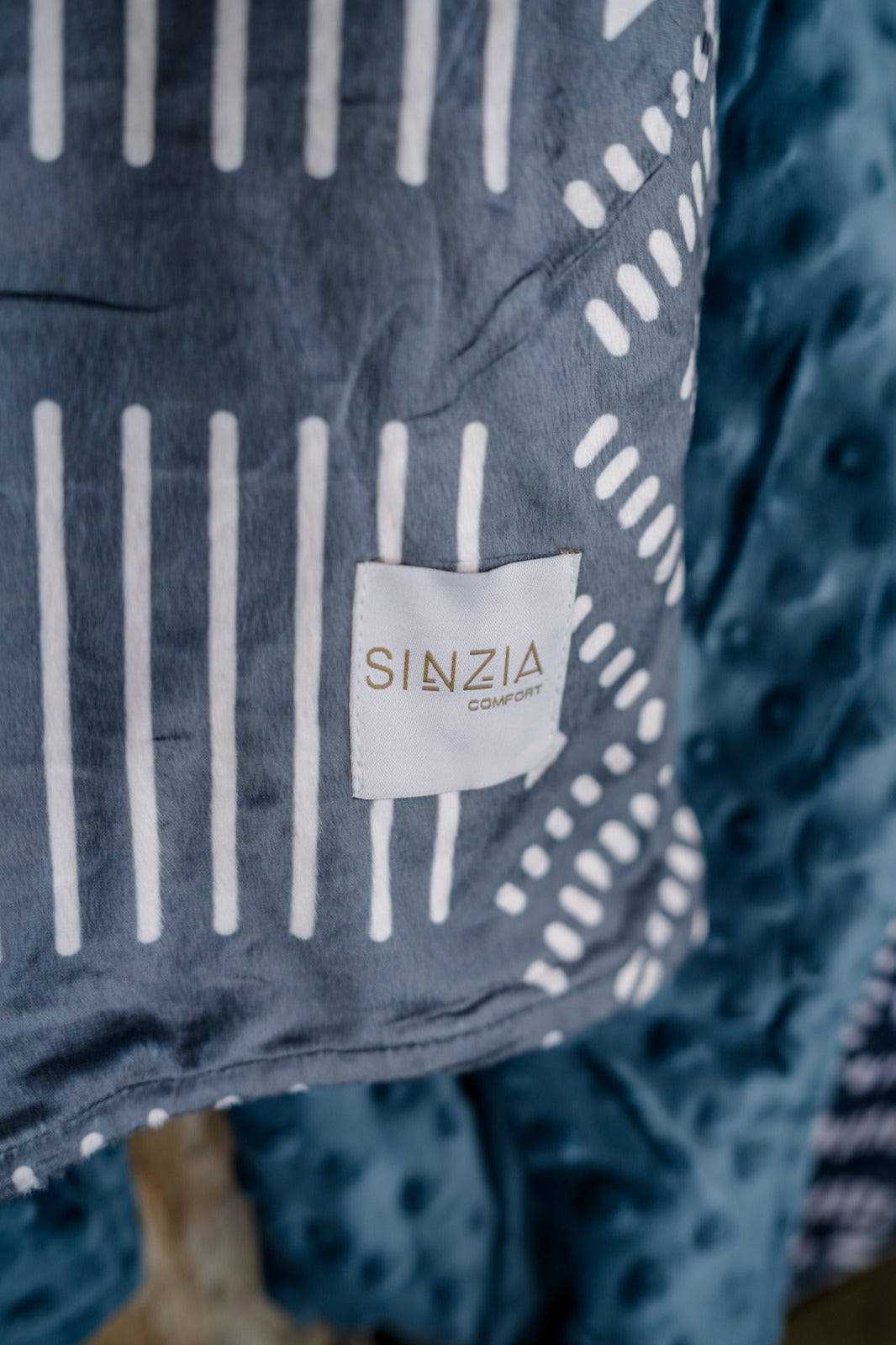 Kijani Throw Blanket in teal with geometric patterned front and solid textured back — large 60" x 80" African-inspired reversible blanket by Sinzia Comfort.